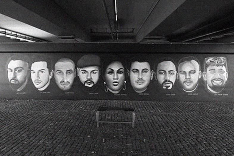 Ein Wandgemälde mit den Gesichtern und Namen der beim Anschlag getöteten Personen. Daneben die Schrift Rassismus tötet. Niemals vergessen. 