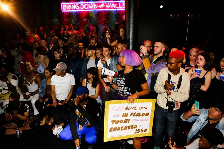 A snapshot from inside an auditorium at an event. In the background, neon letters read "Bring down the walls".