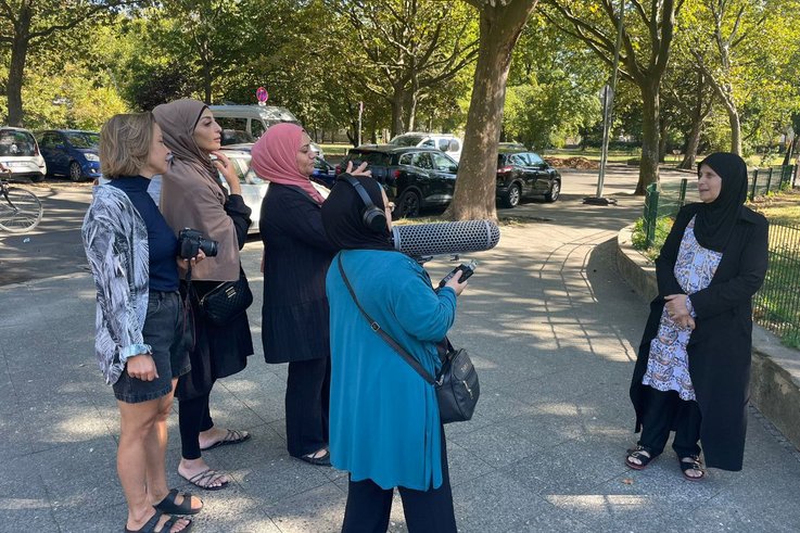 A camera crew of women are outside filming another woman