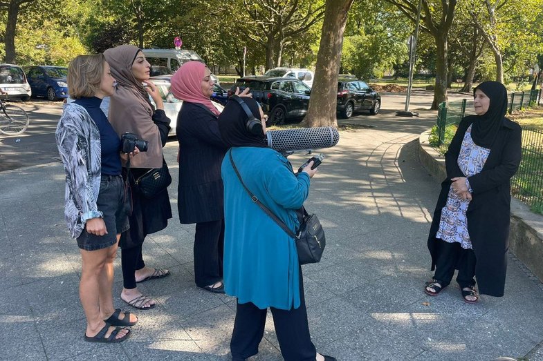 Ein Kamerateam aus Frauen filmt draußen auf dem Mehringplatz eine weitere Frau.