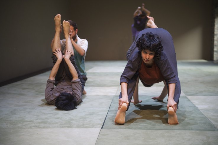 Photograph of five people on the large floor panels. Their bodies are intertwined in pairs.