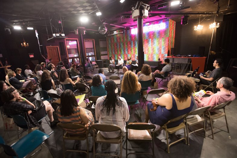 A photo of a discussion event on a stage with audience members.