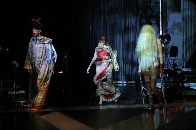 Auf einer Bühne stehen drei kostümierte Schaupieler:innen von She She Pop.