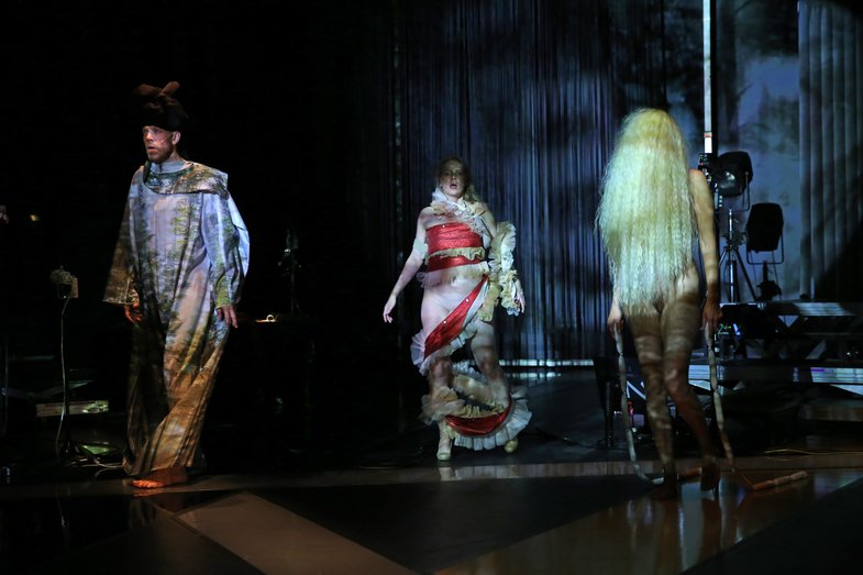 Three costumed She She Pop actors stand on a stage.