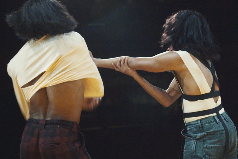 Two Black dancers in yellow tops in motion