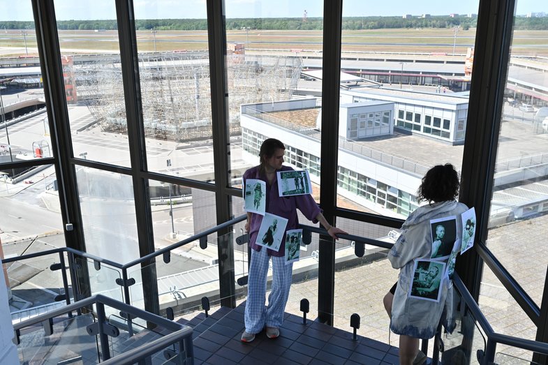 Two people stand in a glass stairwell.