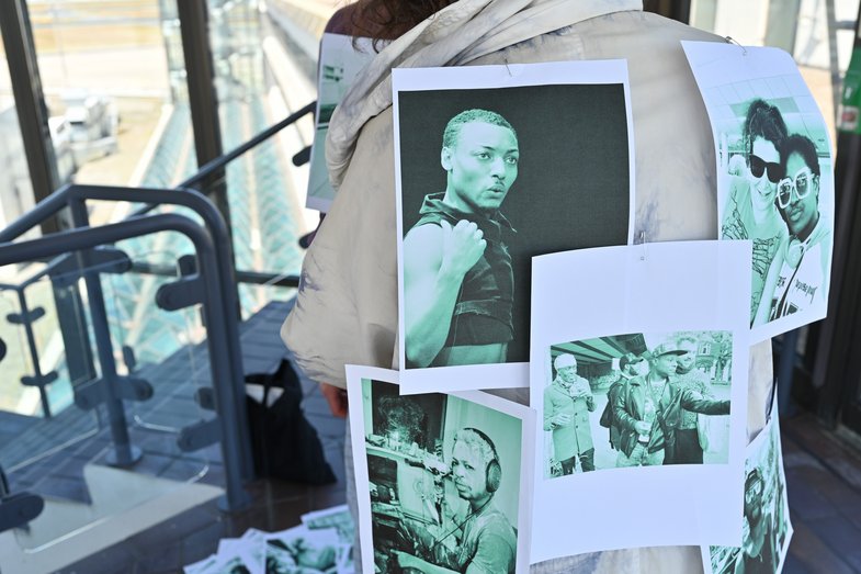 Several printed photos are stuck to a person's coat.