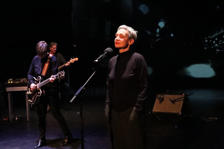 Eine Sängerin mit geschlossenen Augen mit der Band auf der Bühne. 