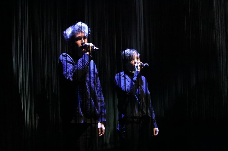 Zwei Personen singen gemeinsam, jeweils in ein Mikrophon.