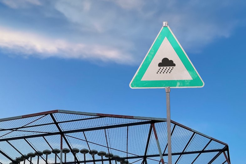 Fotografie eines dreieckigen Schildes. In der Mitte ist ein Piktogramm einer Regenwolke abgebildet.