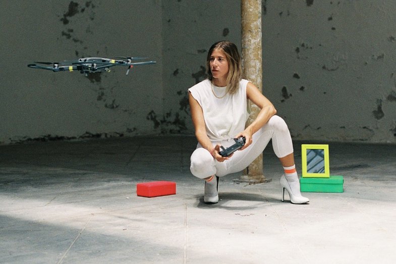 A person crouching lets a remote-controlled quadro-copter fly.