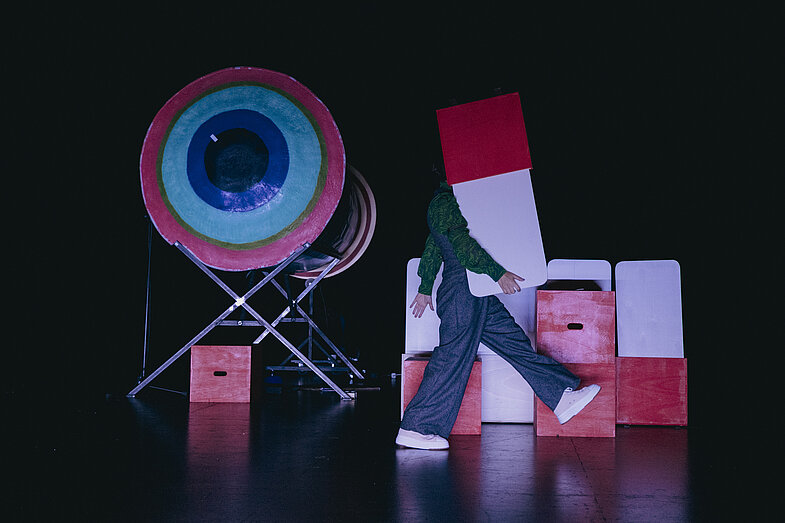 2. A stage filled with props and one person holding a prop which is hiding their face