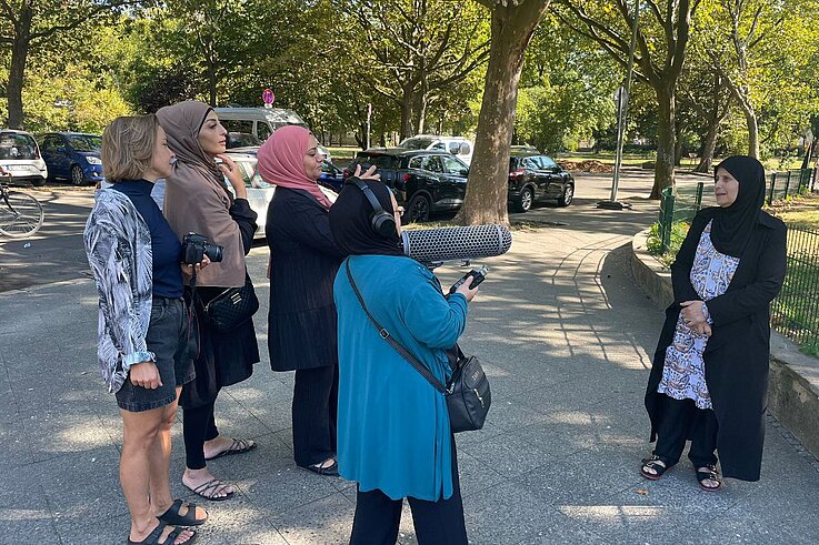 Ein Kamerateam aus Frauen filmt draußen auf dem Mehringplatz eine weitere Frau.