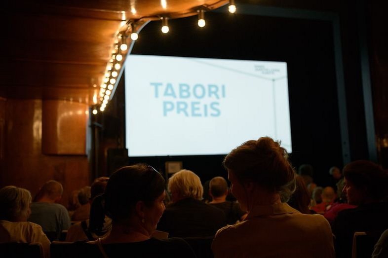Photograph from the auditorium of HAU1. On the stage is a screen with the inscription "Tabori Preis".