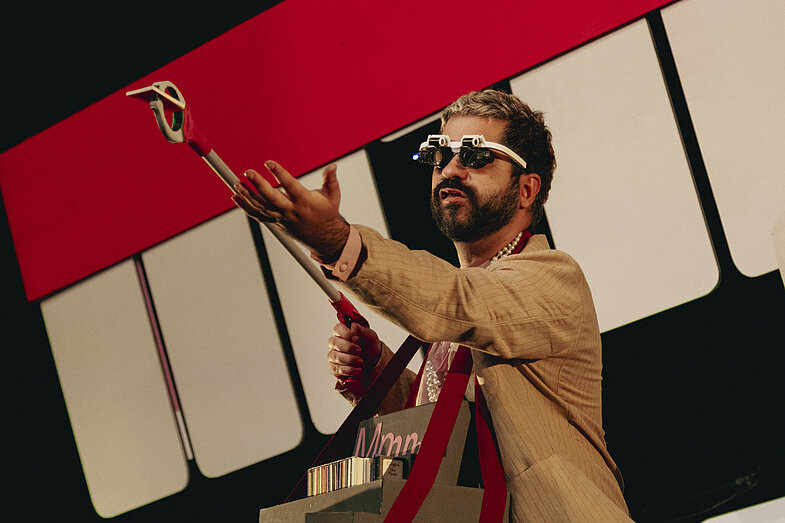 1. A man with sunglasses holds a contraption in one hand and holds out his other hand.